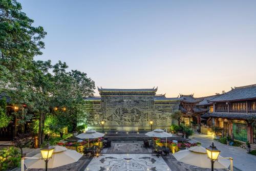 a building with a fountain and tables and umbrellas at Doof Resort Hotel in Lijiang