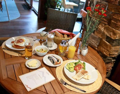 a wooden table with plates of food and drinks on it at Vila GRAND in Smokovce