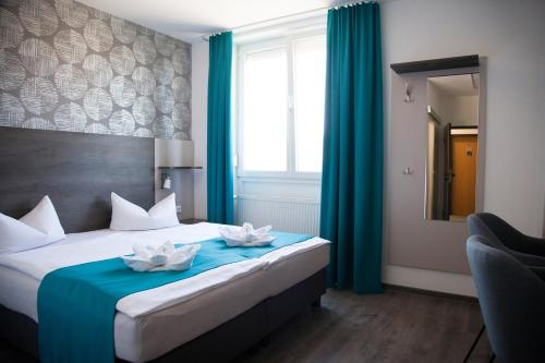 a bedroom with a bed with blue curtains and a mirror at Hotel im Kaiserpark in Meiningen