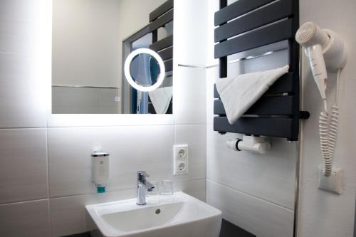 ein Bad mit einem Waschbecken und einem Spiegel in der Unterkunft Hotel im Kaiserpark in Meiningen