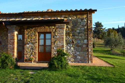 a small stone building with a door in the grass at Aurora Agriturismo in San Casciano dei Bagni