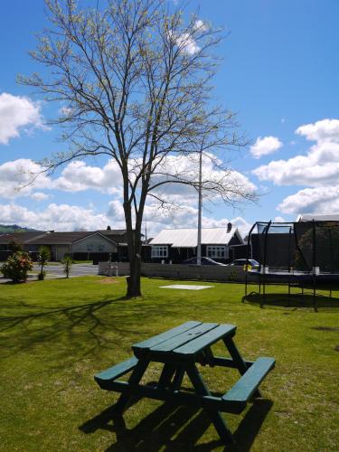 a picnic table in a field with a tree at Gateway International Motel in Rotorua
