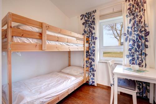 a bedroom with a bunk bed and a desk and a window at Knaus Camping- und Ferienhauspark Rügen in Altenkirchen