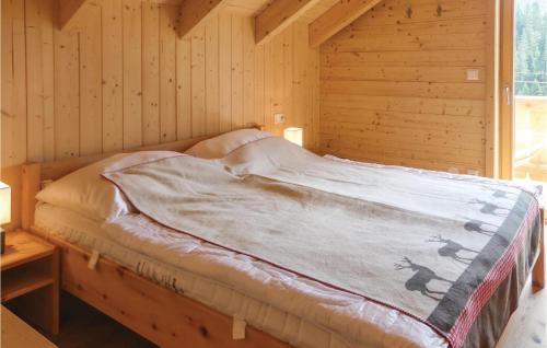 a bed in a room with a wooden wall at Gemuetliches Almhaus in Flattnitz