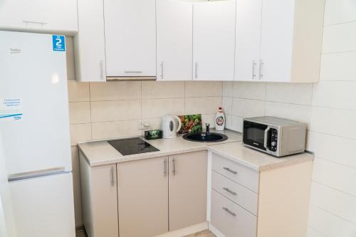a small kitchen with white cabinets and a microwave at Апартаменты Красная, 10Б in Kemerovo