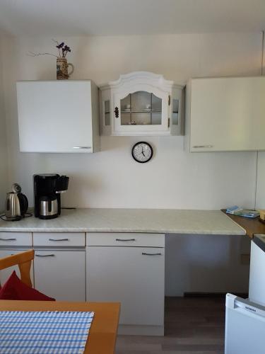 a kitchen with white cabinets and a clock on the wall at Ferienwohnung Kraihof, 83703 Gmund am Tegernsee in Gmund am Tegernsee