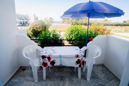 a table and chairs with an umbrella on a balcony at Yiannis Apartments in Mastichari