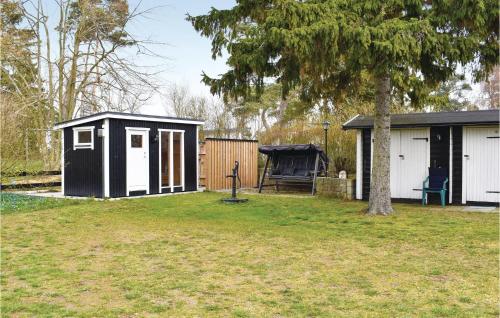 a black and white shed in a yard with a tree at Gorgeous Home In Skivarp With Sauna in Skivarp