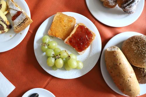a table topped with plates of food with grapes and bread at Albergo Cantiani in Ancona