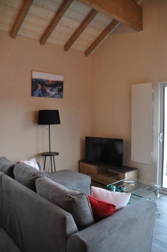 a living room with a couch and a tv at les charmes du lac Sauna et Spa in Gérardmer