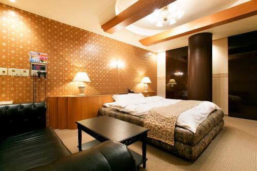 a hotel room with a bed and a couch at Hotel Luna (Adult Only) in Sennan