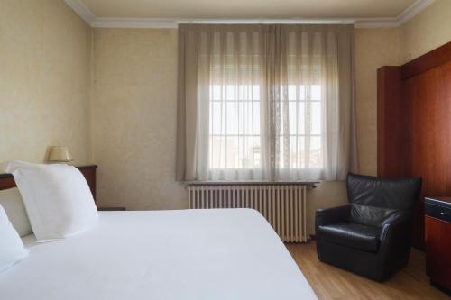 a bedroom with a large bed and a chair at Hotel Astoria in Barcelona
