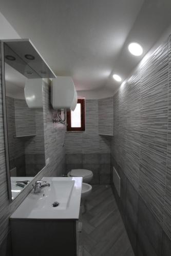 y baño con lavabo, aseo y espejo. en Casetta delle Arti, en Mondragone