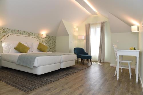 a bedroom with a white bed and a desk and a table at OurMadeira - Babosas Village, gardénias and greenspaces in Funchal