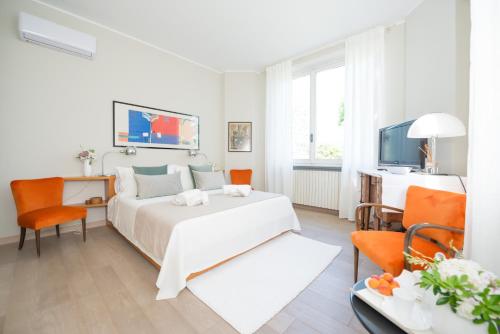 a white bedroom with a white bed and orange chairs at Villa La Maggiorana in Rivoli