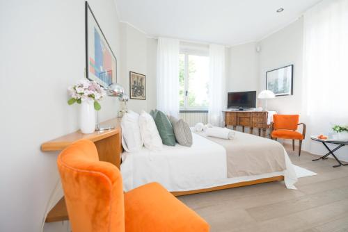a bedroom with a white bed and orange chairs at Villa La Maggiorana in Rivoli