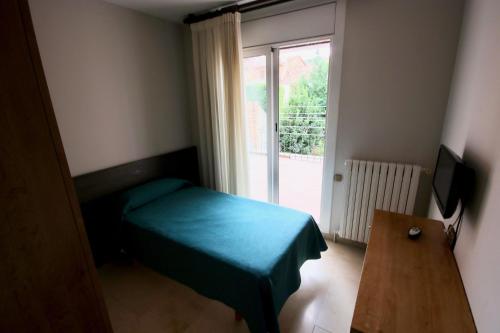 um pequeno quarto com uma cama e uma janela em hostal trevol em Torelló