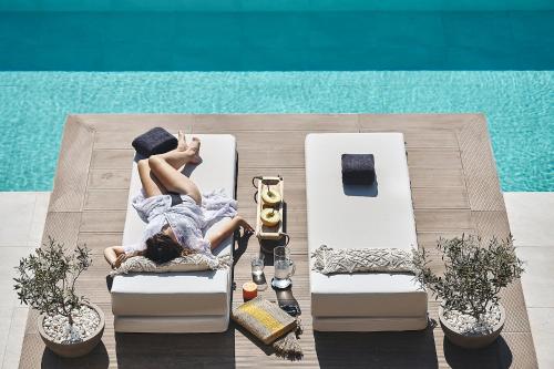 a woman sitting in a chair next to a pool at Villa Niolos II in Stérnai