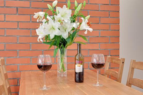 a vase of white flowers and a bottle of wine at Central Apartment - free private parking in Gdańsk