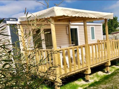 une petite maison avec une terrasse couverte et un toit dans l'établissement Camping Les Carolins, à Saint-Lo-dʼOurville