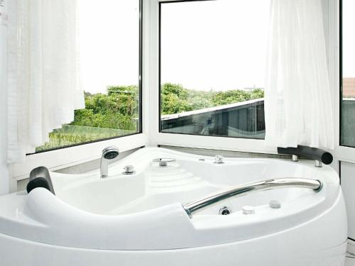 bañera blanca en una habitación con ventana en Four-Bedroom Holiday home in Løkken 28, en Lønstrup