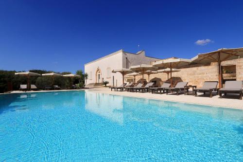 una grande piscina con sedie e ombrelloni di Antica Masseria Pescu a Presicce