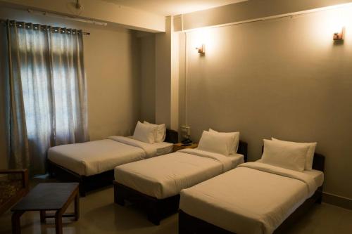 a hotel room with three beds and a table at Hotel Ariel in Kohīma