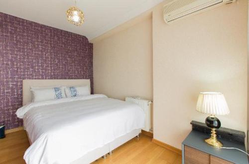 a bedroom with a white bed and a table with a lamp at CTS Elysium Residence Taksim in Istanbul
