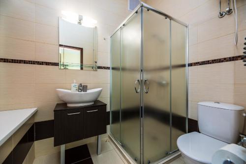 a bathroom with a glass shower and a sink at Amber vila in Šventoji