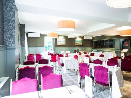 a dining room with pink chairs and tables at The Gables Hotel in Gretna Green