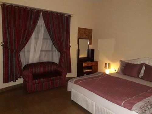 ein Schlafzimmer mit einem Bett, einem Stuhl und einem Fenster in der Unterkunft Ahlam Musandam Villa in al-Chasab