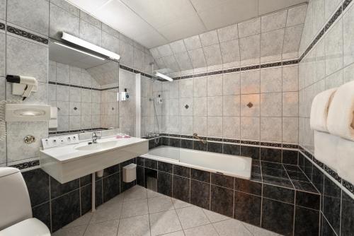 a bathroom with a tub and a sink and a toilet at Quality Hotel Florø in Florø