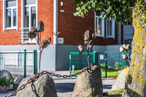 a chain wrapped around two large rocks with flowers at Amber vila in Šventoji