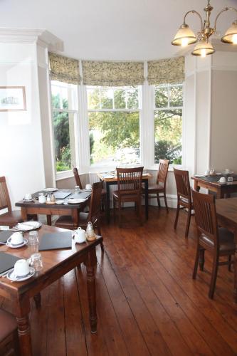 a dining room with tables and chairs and windows at Kirkwood Guest House in Windermere