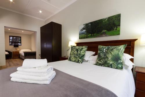 a bedroom with a white bed with towels on it at The Pecan Tree Guesthouse in Johannesburg