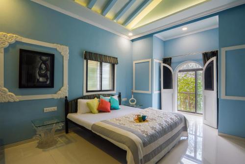 a bedroom with blue walls and a bed with colorful pillows at StayVista's Maximus Villa - City-Center Villa with Private Pool, Gazebo, Games & Projector Room in Lonavala
