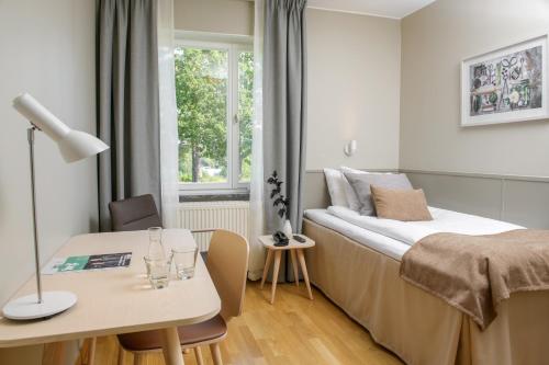 a bedroom with a bed and a table and a desk at Runö Möten & Events in Åkersberga
