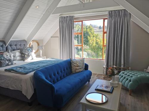 a bedroom with a blue couch and a large window at Zorgvliet Wines Country Lodge in Stellenbosch