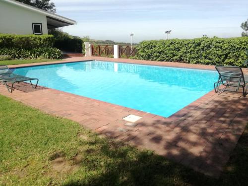 a large swimming pool with two chairs in a yard at Zevenwacht Cottages in Kuilsrivier
