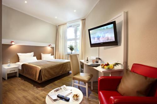 a hotel room with a bed and a tv on the wall at Hotel Domicil Hamburg by Golden Tulip in Hamburg