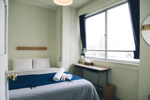 a small room with a bed and a window at Nui. HOSTEL & BAR LOUNGE in Tokyo