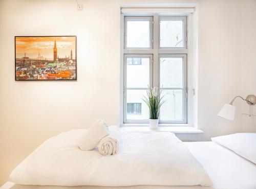 a white bedroom with a large white bed and a window at Renovated 1bedroom apartment in Central Copenhagen in Copenhagen