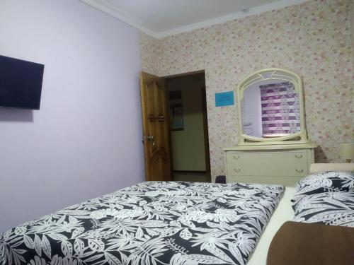 a bedroom with a bed and a dresser and a mirror at Samia House Room on Furqat 8 in Tashkent