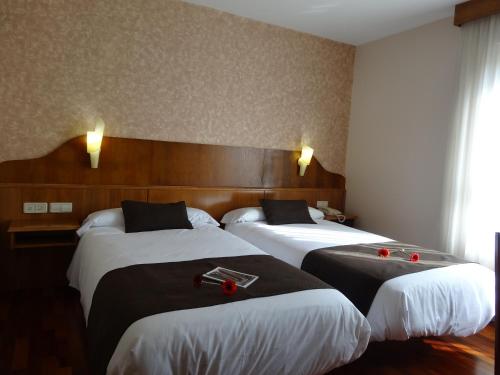 two beds in a hotel room with red candles on them at Hotel El Pescador in Perillo