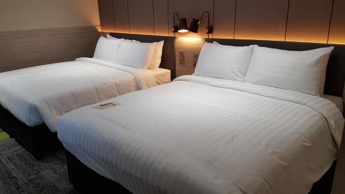 two beds in a hotel room with white sheets at Aerotel London Heathrow Airport, Terminal 2 & Terminal 3 in Hillingdon