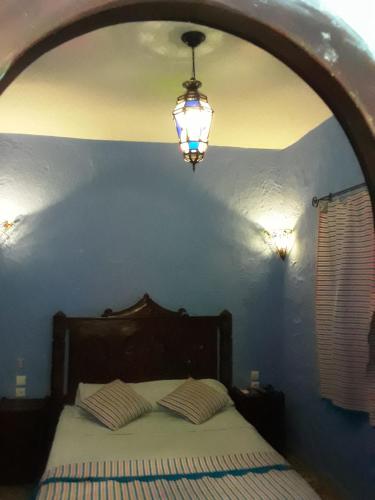 1 dormitorio con 1 cama con luz sobre ella en Dar Lbakal, en Chefchaouen