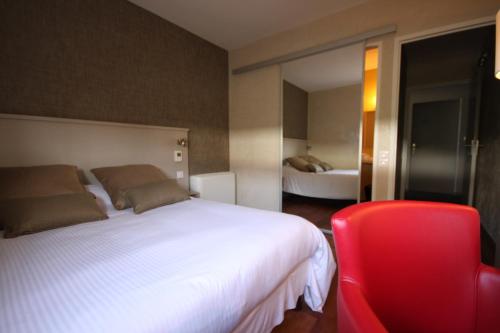 a bedroom with a white bed and a red chair at Hôtel d'Arcins in Latresne
