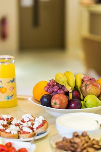 a table topped with plates of fruit and desserts at Eltina Hotel in Rethymno Town