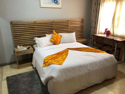 1 dormitorio con 1 cama blanca grande con almohadas de color naranja en Central Hotel - OSU en Accra