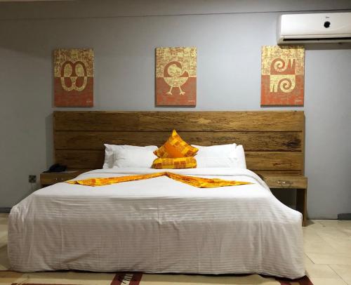 a bedroom with a large bed and two paintings on the wall at Central Hotel - OSU in Accra